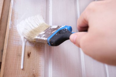 Beyaz akrilik boyalı bir el fırçası ahşap bir duvardan aşağı süzülüyor, ev onarımı, inşaat ve diy, ahşap işleme ve tedavi