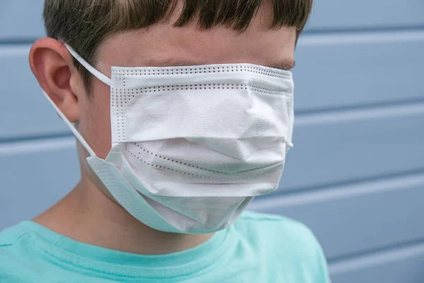 Смішний вигляд хлопчика в білій захисній хірургічній медичній масці, що покриває навіть очі, щоб запобігти зараженню під час епідемії, анекдоту від пандемії — стокове фото
