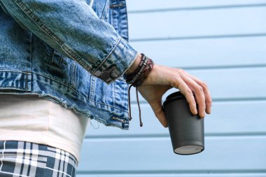 Bileğine deri bilezikler takan hippi bir kadın ve kot ceketli bir kadın. Elinde bir fincan kahve, kafein bağımlılığı, yaz zamanı.