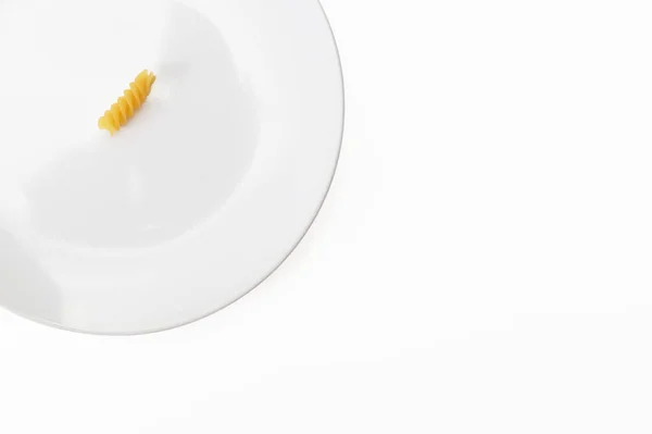 Ένα ωμό uncocked fusilli ζυμαρικά σε λευκό κεραμικό πιάτο που απομονώνονται σε λευκό, αδυνατίζοντας μεσογειακή διατροφή έννοια — Φωτογραφία Αρχείου