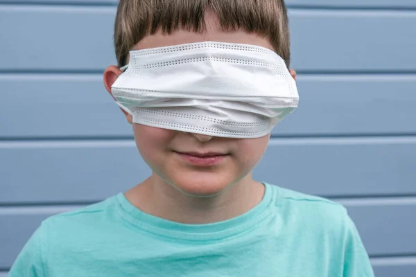 Смішний вигляд хлопчика в білій захисній хірургічній масці на очах замість рота, він лає епідемію та пандемію ковадла, рофль — стокове фото