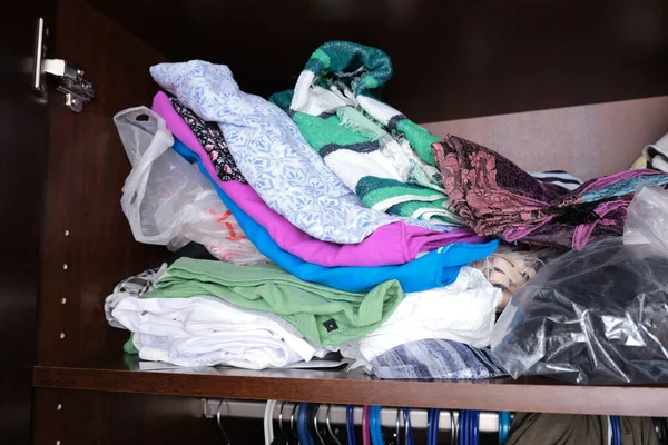 Unorganized heaps of clothes of different colors in a wardrobe lying in mess, storage and order at home — Stock Photo, Image