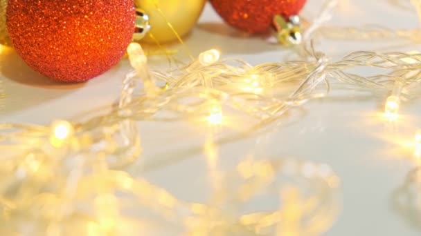 Decorazioni di Natale, palle per un abete di pino su tavolo bianco con una ghirlanda scintillante festiva, un'atmosfera di vacanza, un'atmosfera — Video Stock