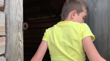 Terk edilmiş ahşap bir kır evinin kapısını açan genç bir çocuk, onu keşfetmek istiyor, maceralar ve riskli yolculuk konsepti.