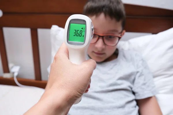Egy normális hőmérsékletű, regenerálódó fiú, amely az infravörös érintésmentes hőmérő kijelzőjén látható, koncepció pf egészséges gyermek — Stock Fotó