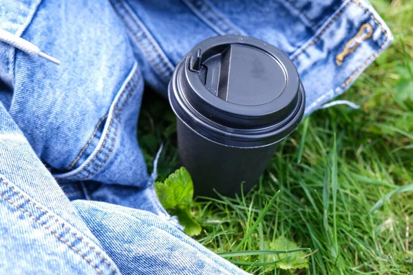 Одноразовая бумажная чашка кофе на вынос на траве в парке в летний день, пикник и отдых на открытом воздухе, на открытом воздухе — стоковое фото