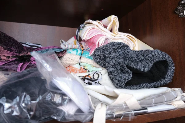 Неорганизованные груды одежды разных цветов в шкафу лежат в беспорядке, хранении и порядке дома — стоковое фото