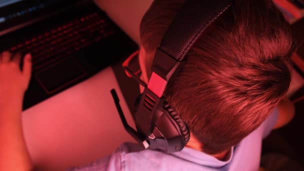 Chłopiec w słuchawkach gra online gra komputerowa w nocy, jest zanurzony w atmosferze wirtualnej rzeczywistości — Wideo stockowe