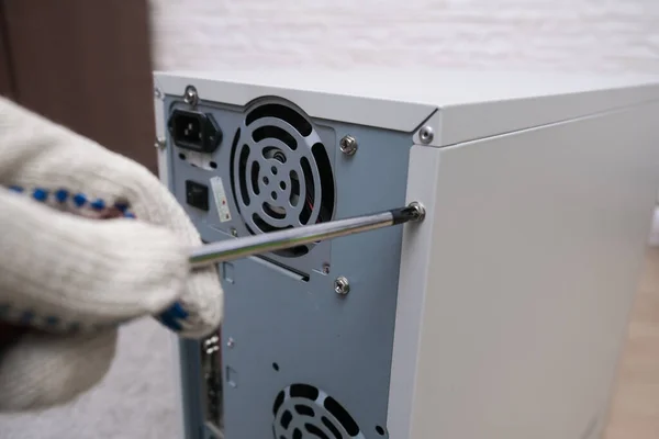 A hand of a repairer opening a case of a computer, system unit repair and upgrading a pc concept.