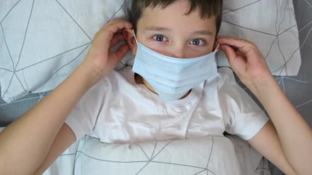 一个生病的高加索男孩躺在床上 戴着医疗保护面具 疾病和流感概念的肖像 — 图库视频影像