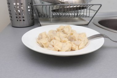 Geleneksel lezzetli haşlanmış Rus pelmeni, ravioli, beyaz seramik tabakta etli hamur köftesi..