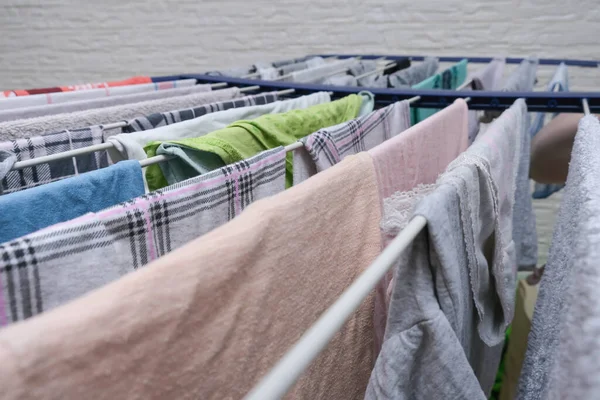 Fresh washed linen, clothes hanging on a dryer, dry apparel on a folding portable dryer close up, housekeeping, homework and chores concept.