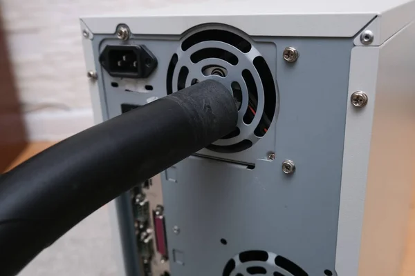 A technician cleaning fan of a computer system box with vacuum cleaner from dust and dirt, Diy and computer maintenance concept.