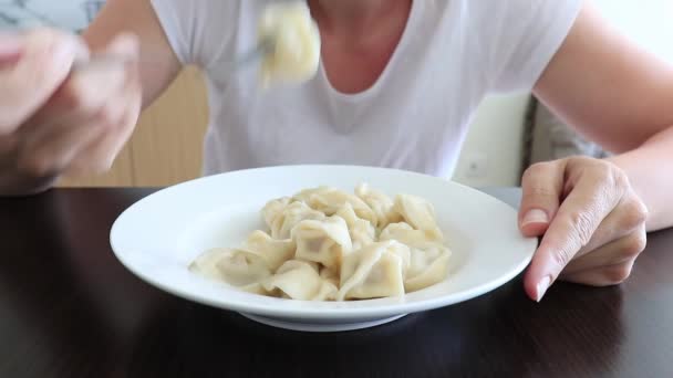 一个饥肠辘辘的女人在厨房里吃饺子 方便而又快速的烹调食物的概念 近距离观察着一个盛满了紫罗兰的陶瓷盘 — 图库视频影像