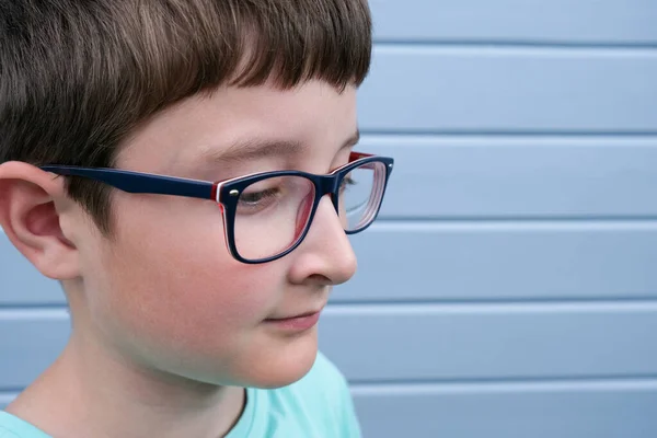 在灰色的蓝色木板上 一个戴眼镜的男孩的肖像画了一面墙 上面有复制空间 散光和眼科疾病 — 图库照片