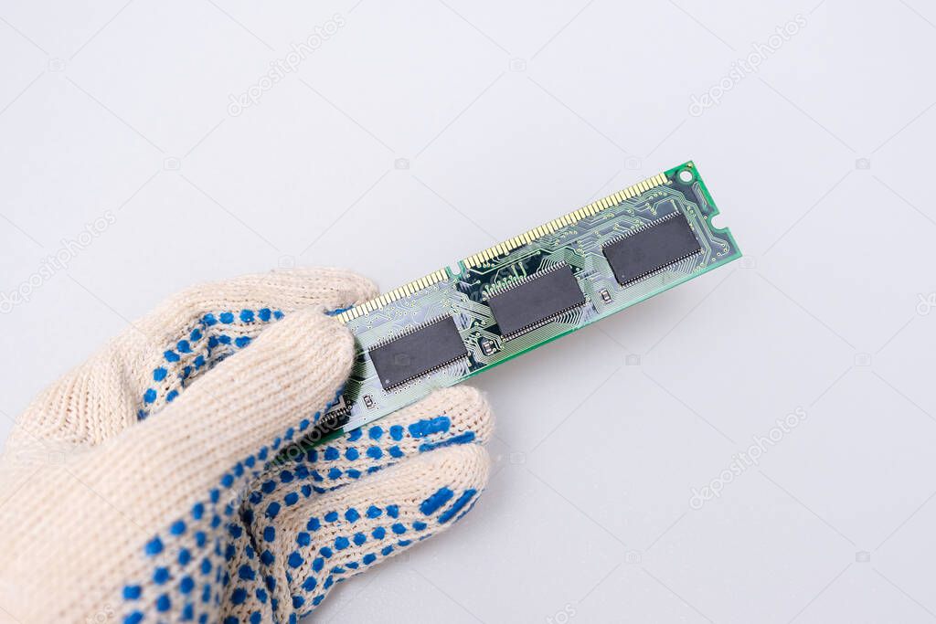 A hand of a repairer technician holding RAM, random access memory in order to upgrade an old computer against whote background, maintanance and repair concept.