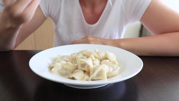 一个饥肠辘辘的女人在厨房里吃饺子 方便而又快速的烹调食物的概念 近距离观察着一个盛满了紫罗兰的陶瓷盘 — 图库视频影像