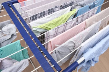 Fresh washed linen, clothes hanging on a dryer, dry apparel on a folding portable dryer close up, housekeeping, homework and chores concept. clipart