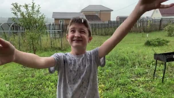 Счастливый Улыбающийся Мальчик Стоит Проливным Дождем Ловит Капли Дождя Ливень — стоковое видео