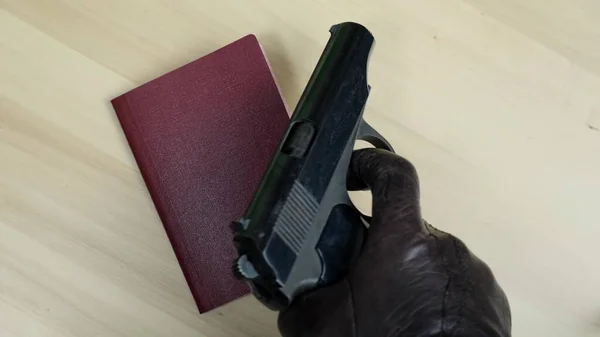 Dłoń Czarnej Rękawicy Kładąc Międzynarodowy Paszport Federacji Rosyjskiej Pistolet Makarow — Zdjęcie stockowe