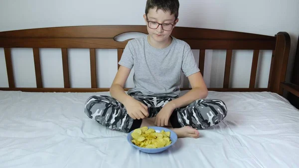 Menino Sentado Sofá Casa Comendo Batatas Fritas Crocantes Uma Tigela — Fotografia de Stock