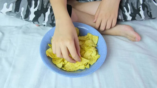Menino Sentado Sofá Casa Comendo Batatas Fritas Crocantes Uma Tigela — Fotografia de Stock