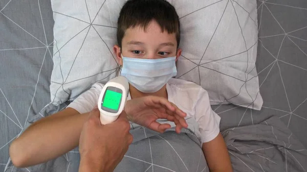 Un niño en recuperación con temperatura normal que se muestra en una pantalla de termómetro infrarrojo sin contacto, concepto pf niño sano, madre que mide la temperatura de su hijo —  Fotos de Stock