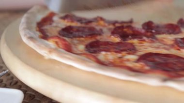 Bir dilim pizzayı kesen ve tabağına götüren biri yakın çekim yapar ve pizza konsepti sunar.