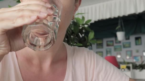 Una mujer sedienta bebiendo agua mineral pura y fresca de un vaso en un restaurante, vista de cerca — Vídeos de Stock