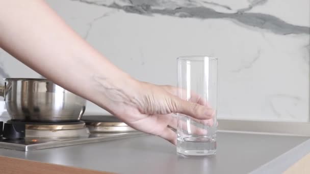 En person häller renat färskt dricksvatten i ett glas från en kanna, kanna i köket — Stockvideo