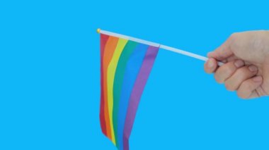 Elinde lgbt gökkuşağı bayrağı tutan lezbiyen kadın, mavi arka plana karşı özgürlük ve cinsiyet eşitliğinin simgesi.