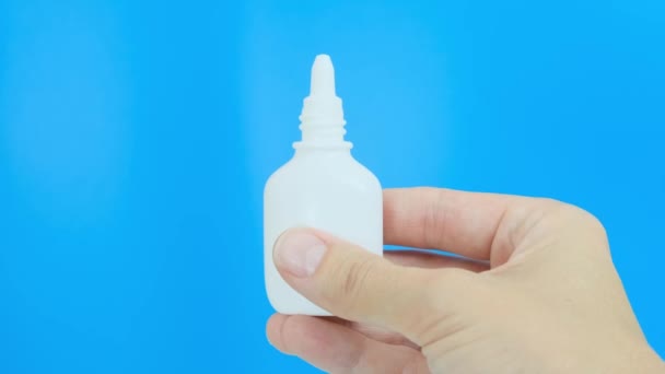 Hand, vingers duwen witte plastic neusspray tegen blauwe achtergrond - sinusitis, geniantritis, rhinitis en andere ziekten van ENT organen concept — Stockvideo