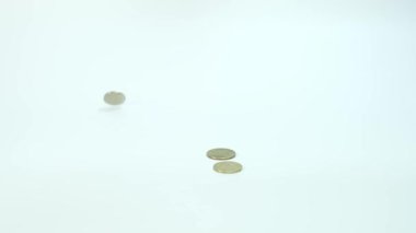 Bozuk paralar beyaz arkaplana karşı yavaş çekimde düşüyor, iş ve mali konsept için tasarruf ediliyor, emeklilik planlaması için tasarruf ediliyor