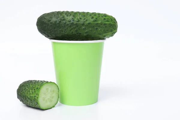 Pepino verde y un vaso de papel de agua potable sobre fondo blanco con espacio para copiar como concepto de adelgazar la dieta y perder peso — Foto de Stock