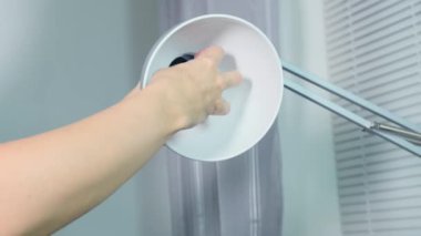 Kadın eli değişiyor, ofiste ya da evde kurşun bir ampulü değiştiriyor, ampulü vidalıyor ve bir lamba tutacağına takıyor.