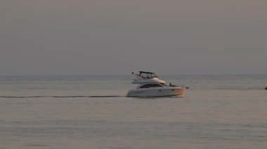 Sochi, Rusya - 14 Haziran 2019: Motor yatı, akşam güneşinde denizde küçük dalgalarla mavi deniz yüzeyinde yol alıyor.