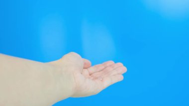 Pompa kutusunda mavi arka plana karşı dezenfektan jeli kullanan eller