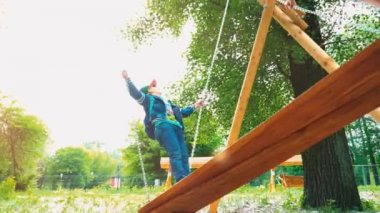 Anne büyük ahşap salıncak bir yaz parkta üzerinde sallanan 5 yaşındaki oğlu olan. Genç kadın bir çocukla birlikte salıncakta ayakta. Etkin aile tatil