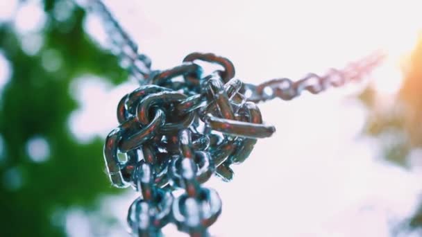 Stevige stalen kettingen hangen naar beneden zijn verbonden in een enkele knoop. Metalen vatting voor een childrens attractie in het park van de zomer — Stockvideo