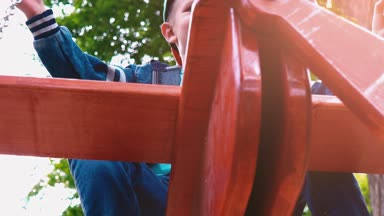 Güneş ışığı altında bir parkta bir uçak şeklinde ahşap bir salıncak üzerinde boy mutlu gülümseyerek. Bir çocuk bir salıncak, yavaş hareket eğleniyor