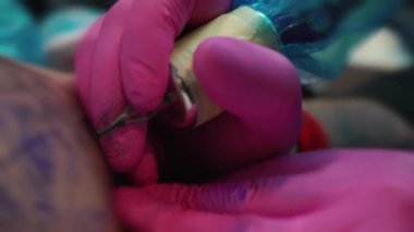 Eller müşteri için dövme yapıyor sanatçı dövme sanatçısı pembe eldiven yapar bir dövme dövme salonunda yakın çekim