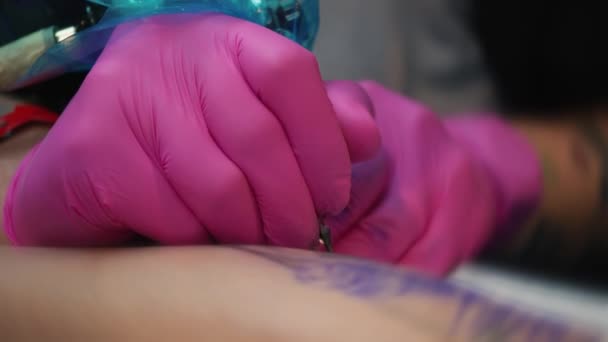 A művésznek, aki a tetoválás az ügyfél kezében, tetováló művész, rózsaszín kesztyű teszi egy tetoválás tattoo szalonban, közelkép