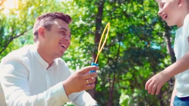 Père avec son fils soufflant des bulles de savon, passe-temps familial amusant, un enfant qui s'amuse avec son père — Video