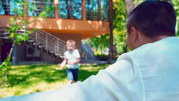 Boy running to his fathers arms and hug him, A happy child meets his father near the house — Stock Video