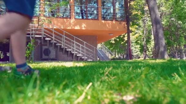 Père avec son fils et sa petite fille courant le long de l'herbe verte se tenant la main près de la maison — Video