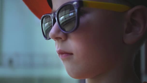 Het portret van het kind in zonnebril, dat is zowat te glimlachen, de jongen weerhoudt zijn emoties — Stockvideo