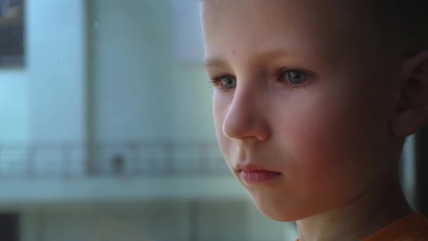 Ein Kind mit sehr traurigen Augen verabschiedet sich am Flughafen von jemandem, ein Nahporträt eines Jungen, zerbrochene Hoffnungen der Kinder — Stockvideo