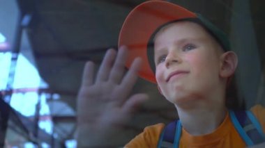 Havaalanında, gülümsüyor ve dalgalar, Çocuk uygun cam aracılığıyla çocuk bakar görür birileri havaalanında kapalı