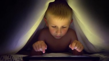 Tablet bilgisayar oyunu oynamak genç bir sarışın çocuğun kapsar.