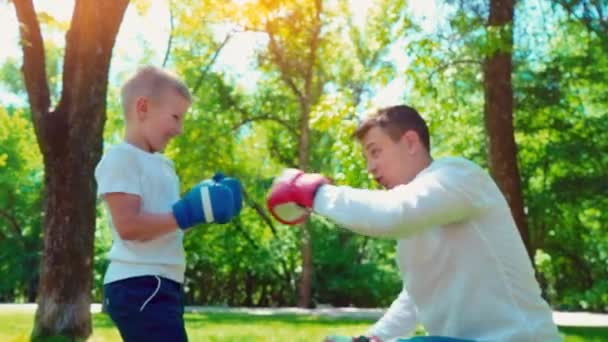 Отец и сын в боксёрских перчатках играют в бокс на лужайке возле дома — стоковое видео